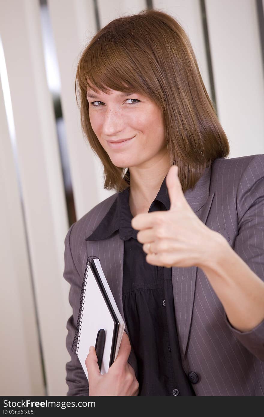 Happy businesswoman with thumb up in office