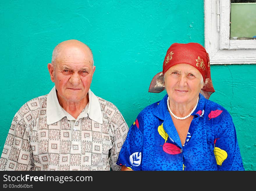 Old peasant couple with their old house in the background