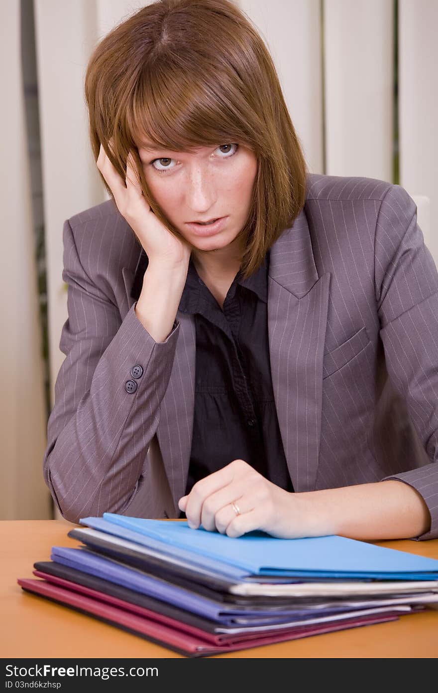 Overworked and frustrated woman with files on the desk. Overworked and frustrated woman with files on the desk