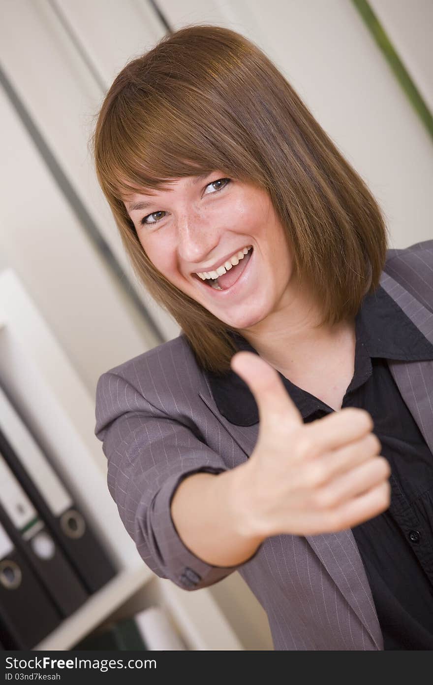 Happy businesswoman with thumb up gesture in office. Happy businesswoman with thumb up gesture in office