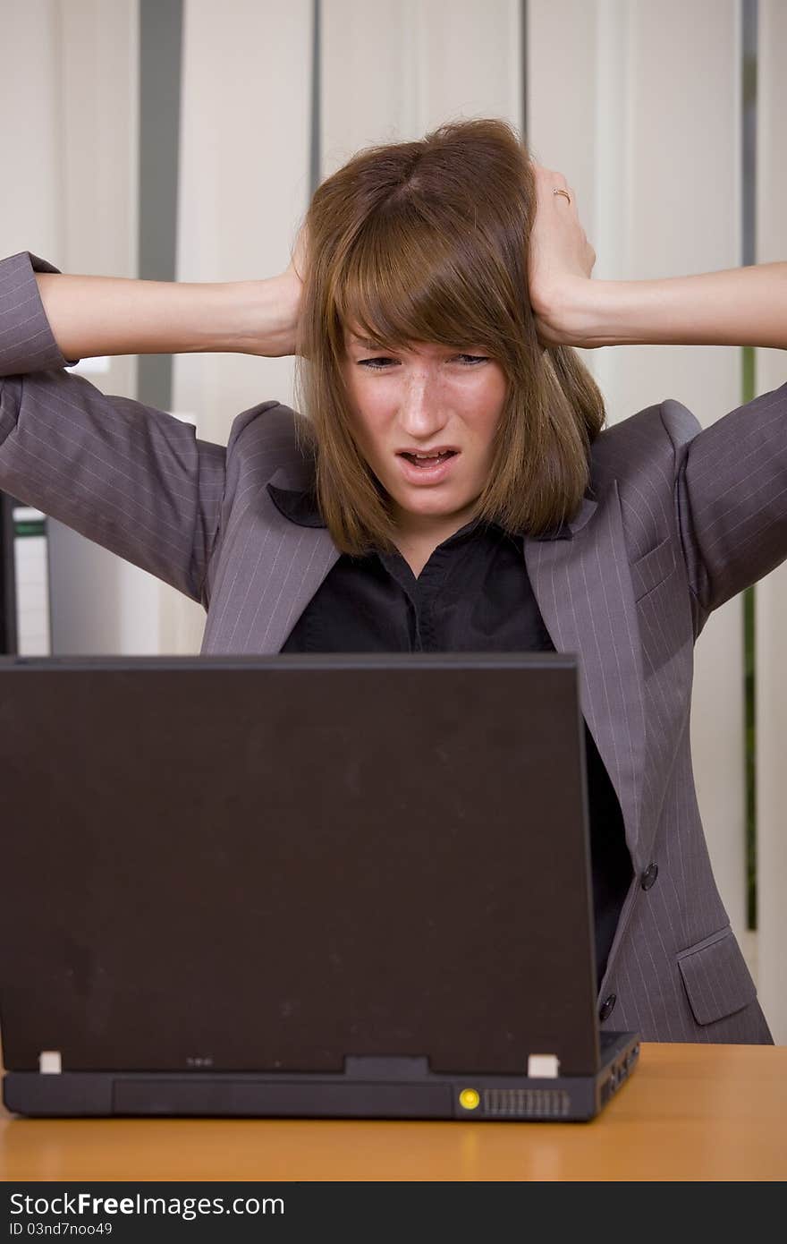 Stressed businesswoman holding her head with both hands looking at laptop. Stressed businesswoman holding her head with both hands looking at laptop