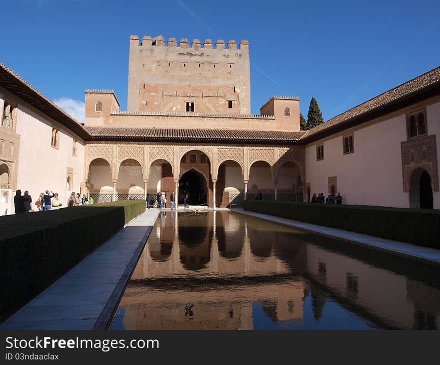 Water in a courtyard inside the Alhambra palace reflecting its surroundings in early morning light.