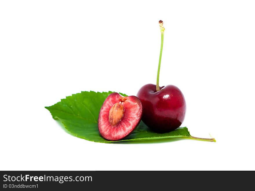 One red cherry and a half on a leaf  on white