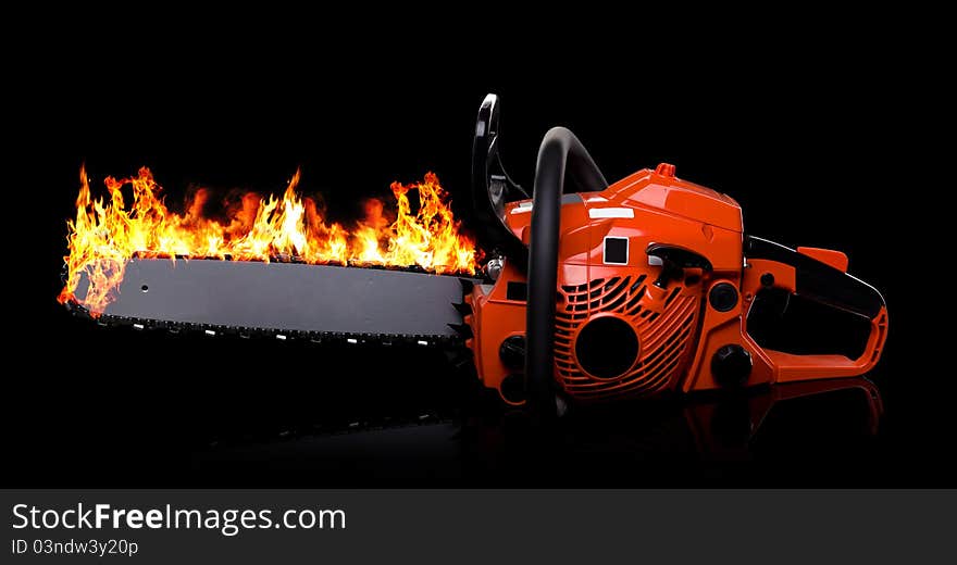 Red chainsaw in fire on black.