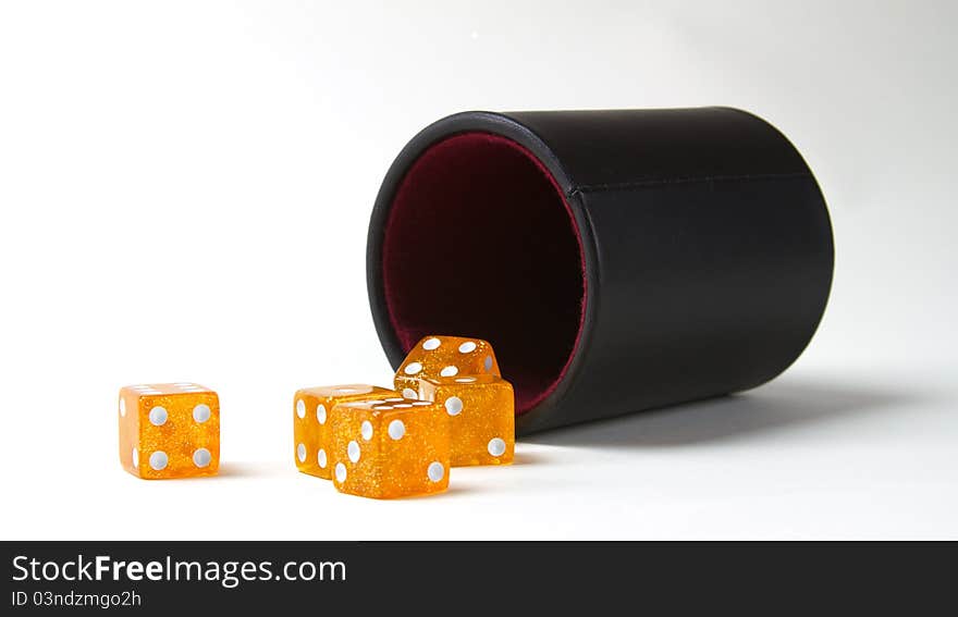 Five orange dice on a white background with a black rolling cup. Five orange dice on a white background with a black rolling cup