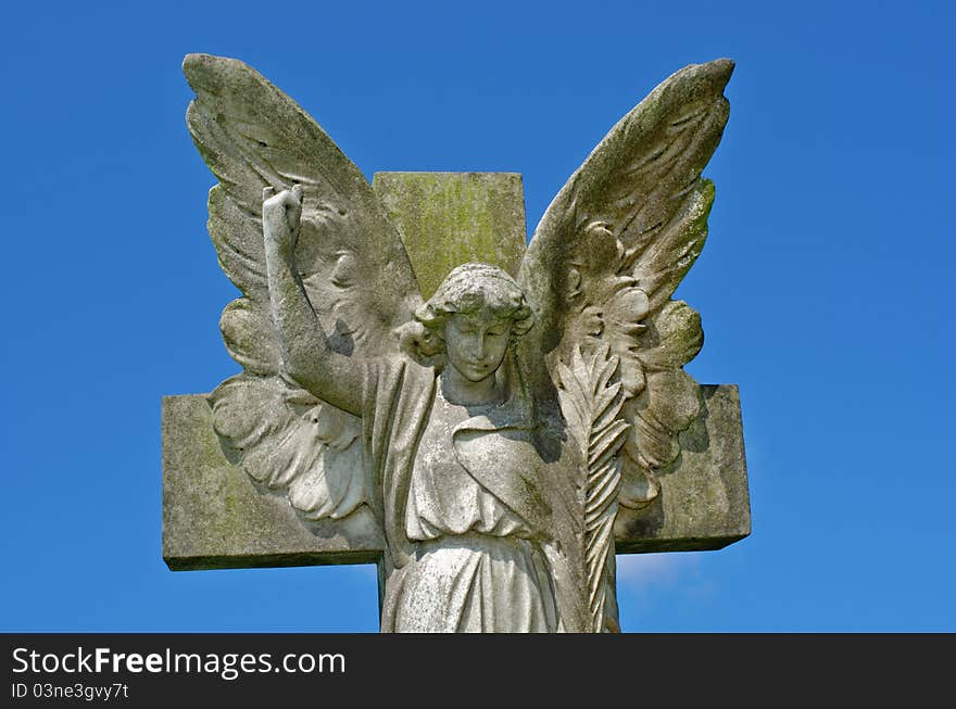 Pre 1900 stone statue of an angel with wings against a bright blue sky with clouds from a grave in the famous landmark Milltown Cemetery Belfast, which is the largest Catholic burial ground in Belfast and synonymous with Irish Republicanism. Pre 1900 stone statue of an angel with wings against a bright blue sky with clouds from a grave in the famous landmark Milltown Cemetery Belfast, which is the largest Catholic burial ground in Belfast and synonymous with Irish Republicanism.