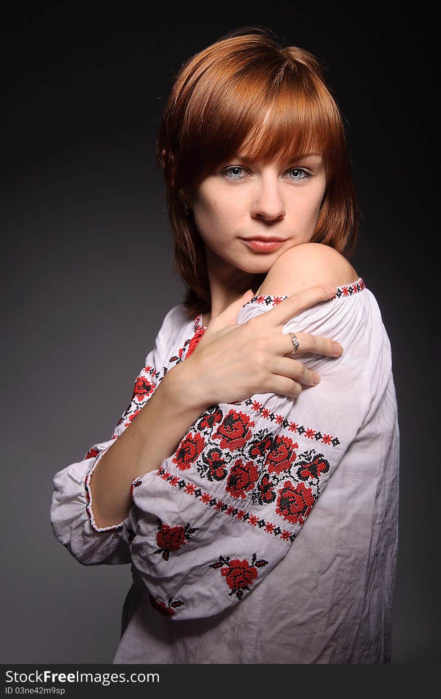 Beautiful red-haired girl with blue eyes wearing ukrainian national cross-stitched costume. Beautiful red-haired girl with blue eyes wearing ukrainian national cross-stitched costume