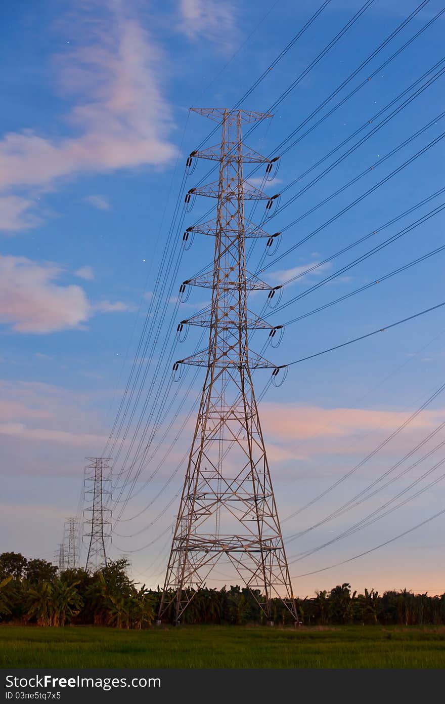 Electricity supply pylons in countryside with blue sky background