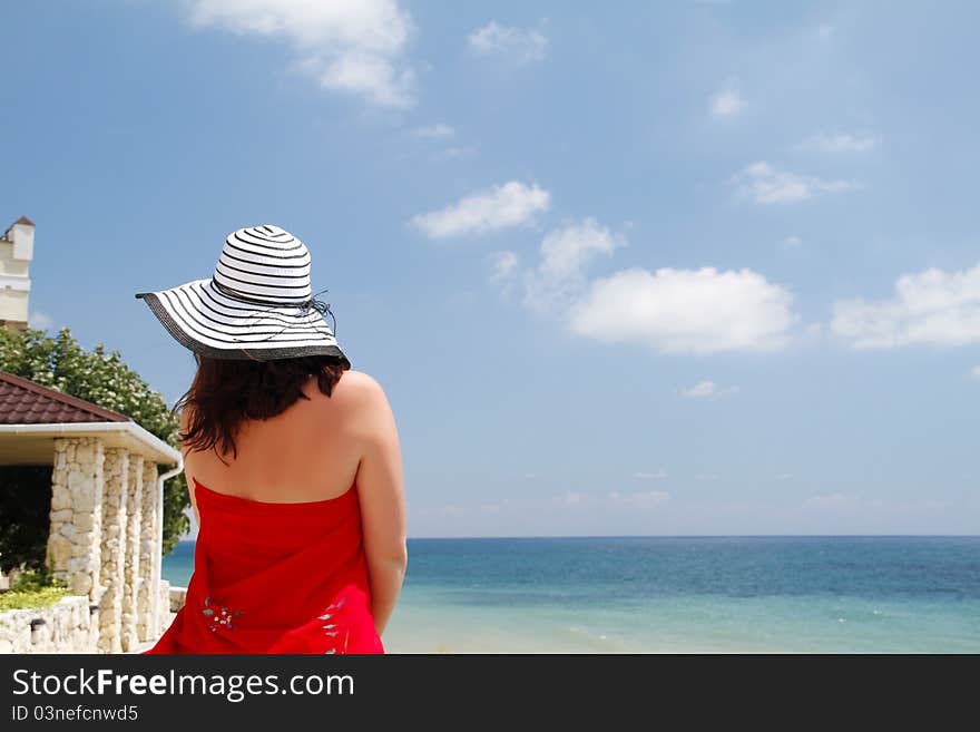 Young woman stands back looking at the sea. Young woman stands back looking at the sea