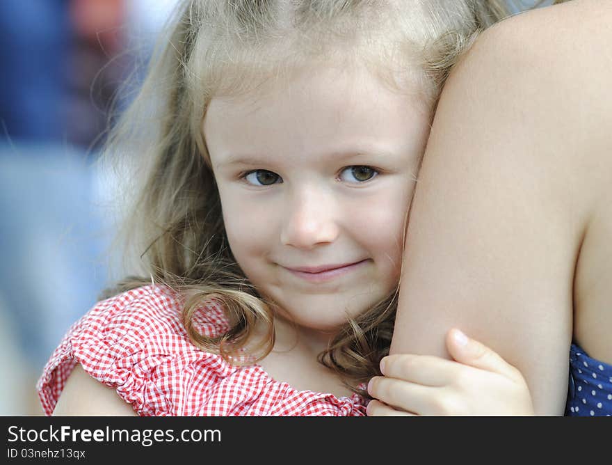 Portrait of a confused little girl holding mothers hand.