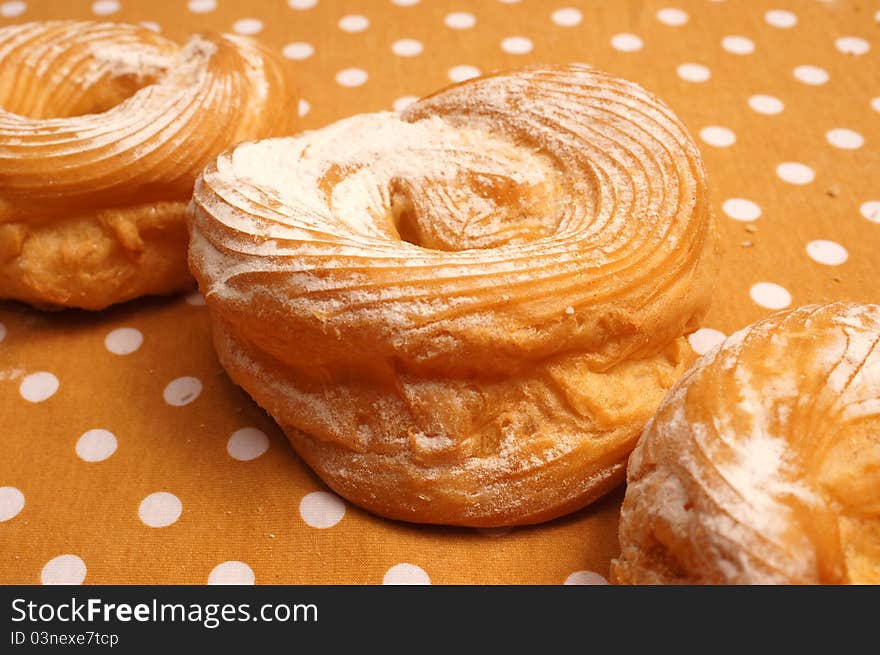 Three doughnuts with sugar on the tablecloth