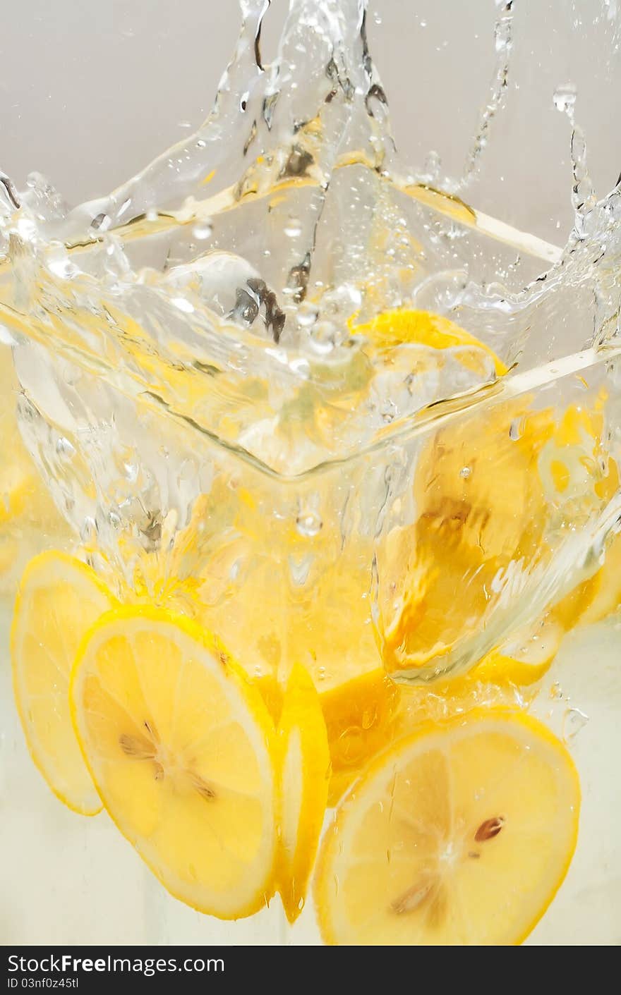 Lemon slices thrown in a transparent bowl causing water-splash. Lemon slices thrown in a transparent bowl causing water-splash