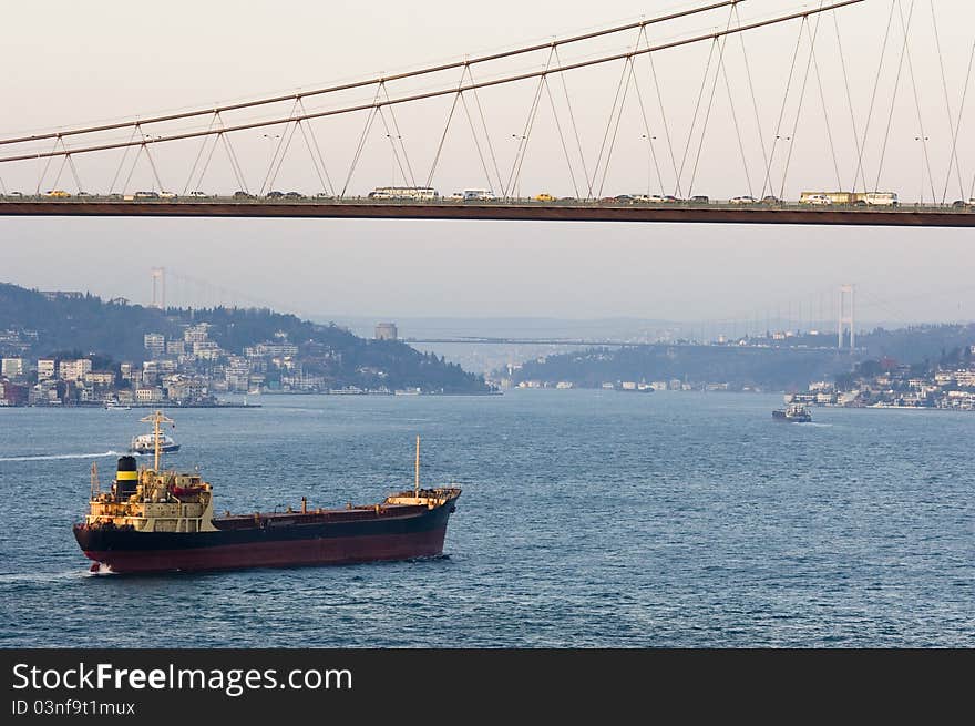 The Bosporus Bridge whcih spans the Bosphorous. Industrial ship passing through straits of Bosphorus... Bosporus Bridge behind, Rumeli Fortress, Fatih Sultan Mehmet Bridge. The Bosporus Bridge whcih spans the Bosphorous. Industrial ship passing through straits of Bosphorus... Bosporus Bridge behind, Rumeli Fortress, Fatih Sultan Mehmet Bridge...