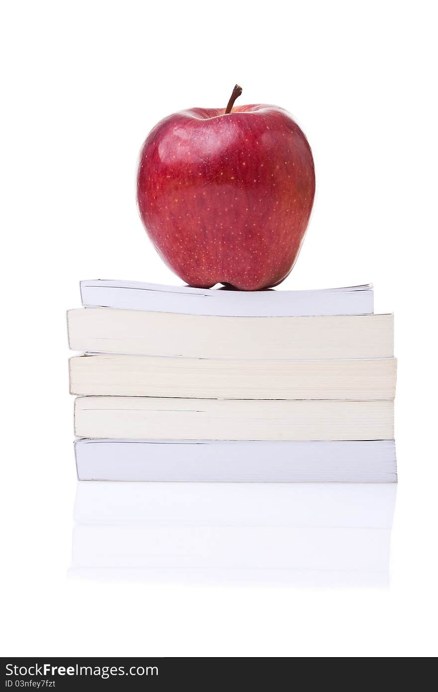 Red apple on the top of a stack of books against a white background