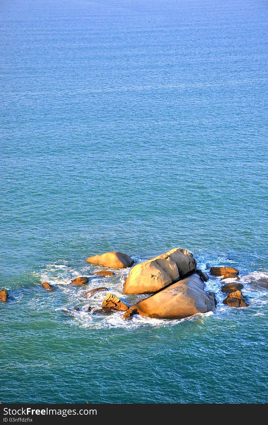 Rocks in blue sea water under sunrise lighting, shown as color, texture comparing between water and rock. Rocks in blue sea water under sunrise lighting, shown as color, texture comparing between water and rock.