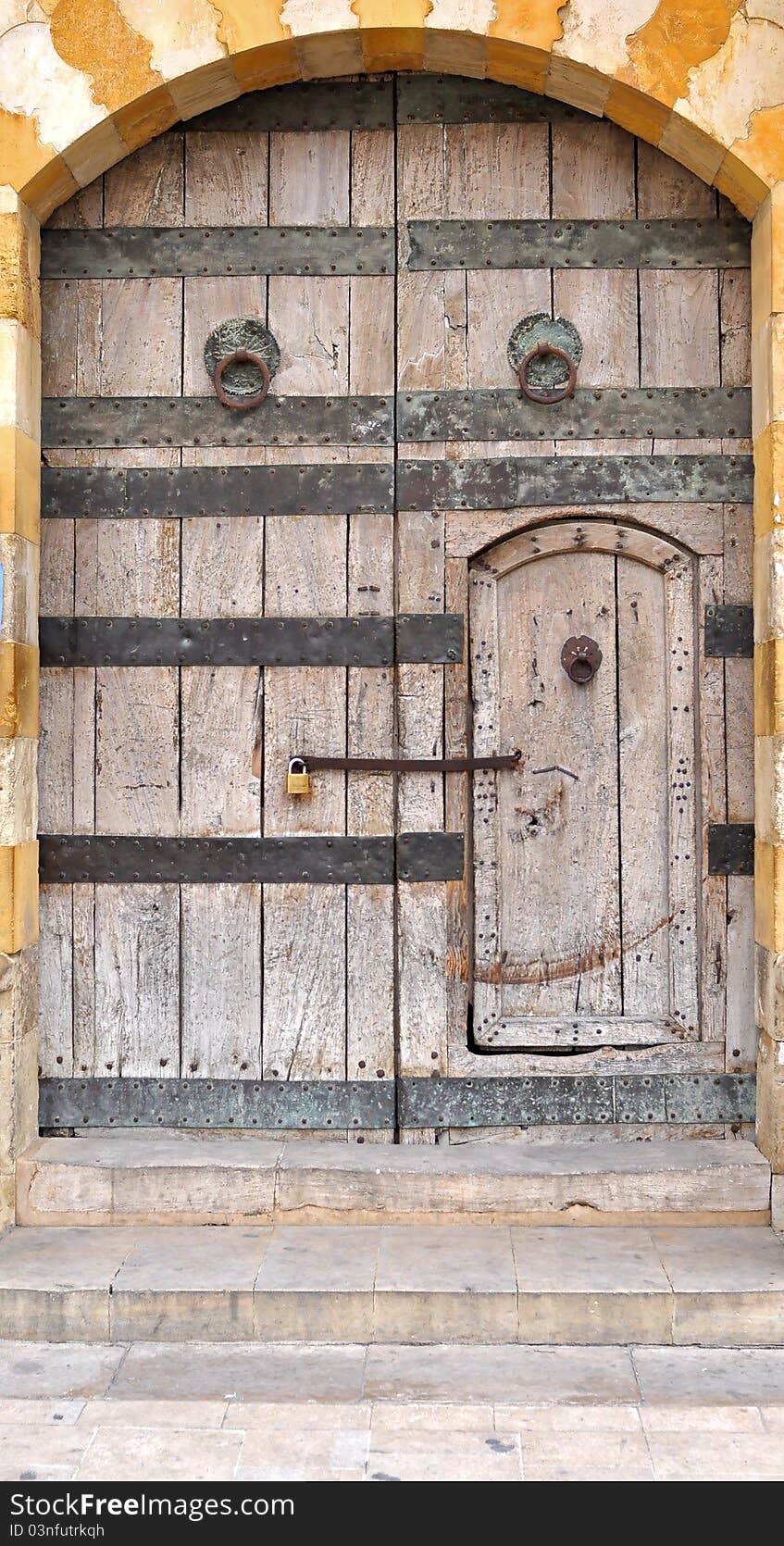 An old wooden gate and a built in another small door. An old wooden gate and a built in another small door.