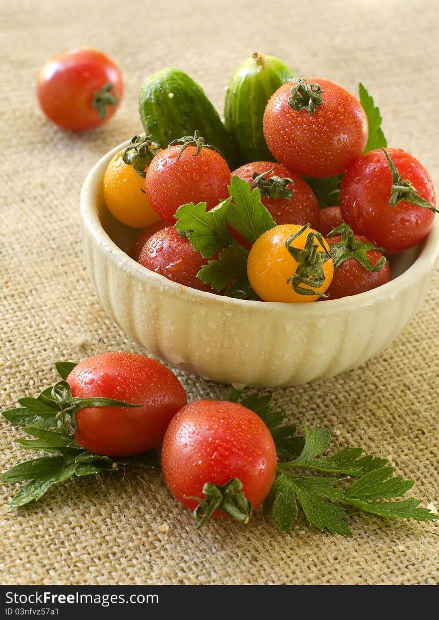 Cherry tomatoes and cucumber in a bowl with parsley. Selective focus. Cherry tomatoes and cucumber in a bowl with parsley. Selective focus