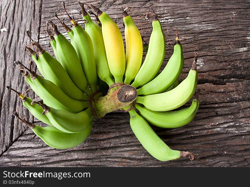 of small green bananas on old wood table. of small green bananas on old wood table