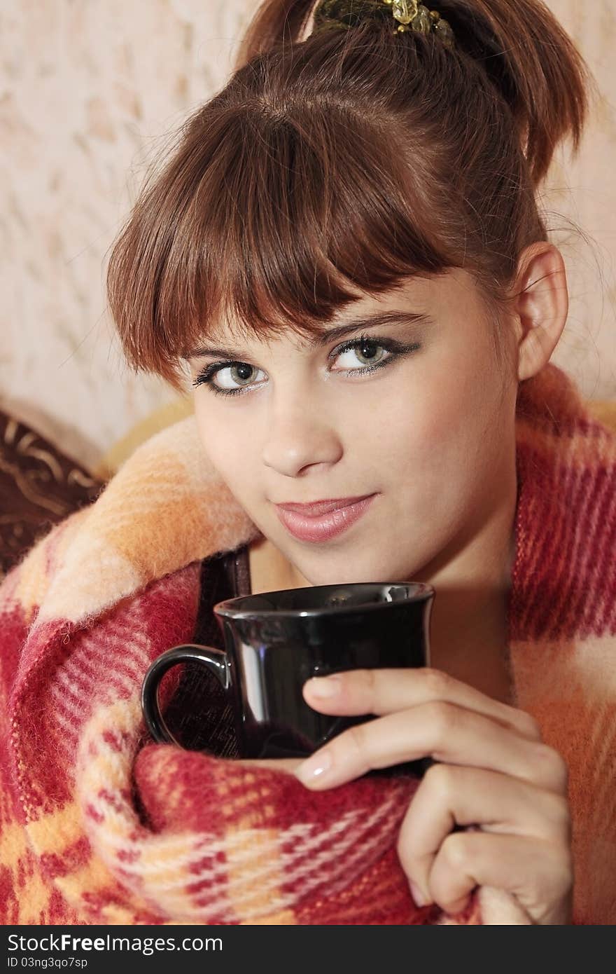 Girl wrapped in plaid with a cup of tea