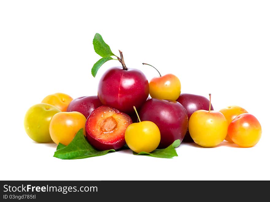 Pile of fresh red and yellow plums with leafs isolated on white background