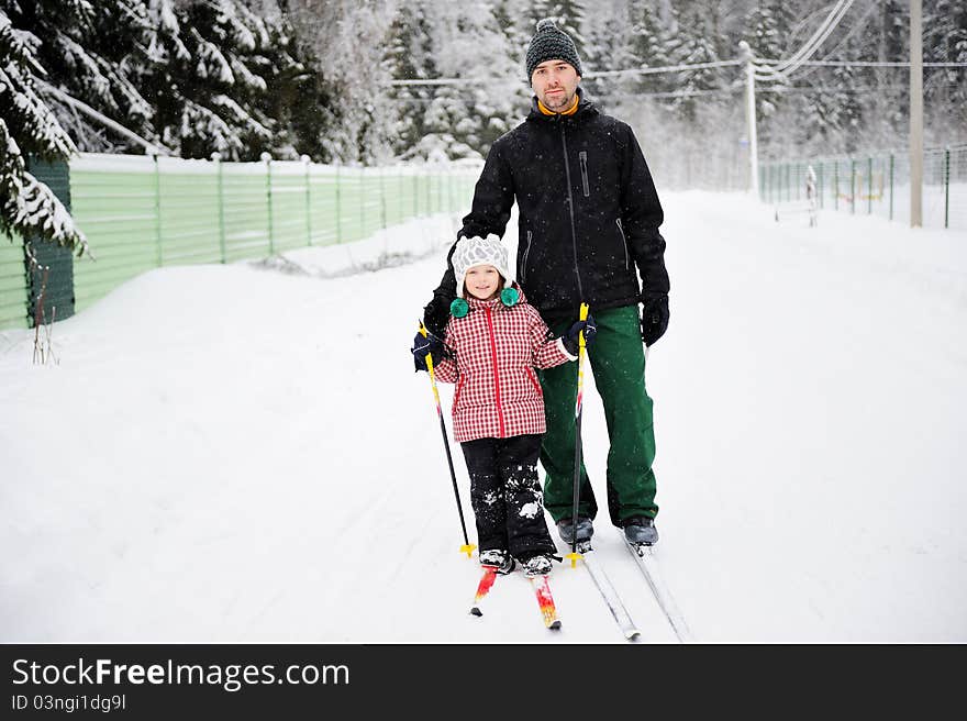 Father and daughter enjoy skiing in rural area on winter day. Father and daughter enjoy skiing in rural area on winter day