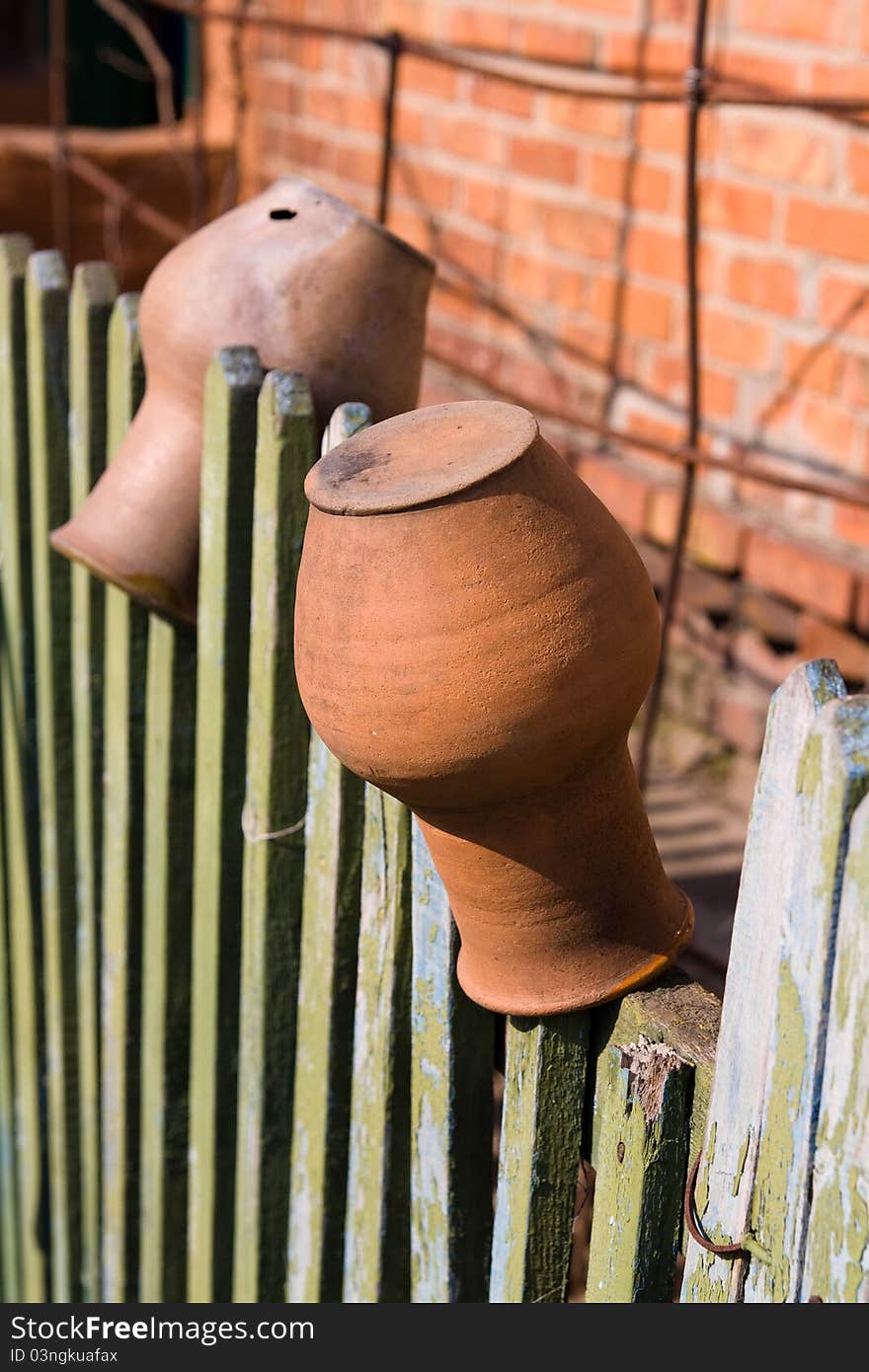 Two jugs weigh and dry on an old rural fence.