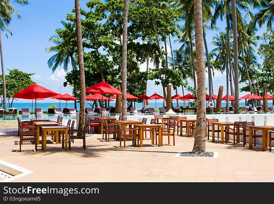 Terrace of a restaurant with red sun shades on a beautiful beach