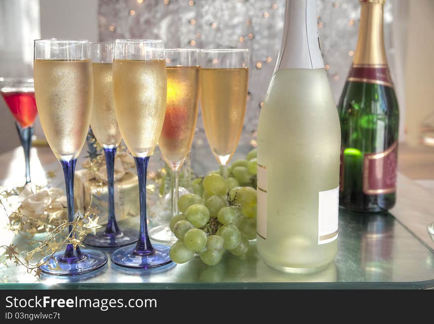 Champagne and wine in glasses,bottles and grapes on silver background with blurred lights. Champagne and wine in glasses,bottles and grapes on silver background with blurred lights.