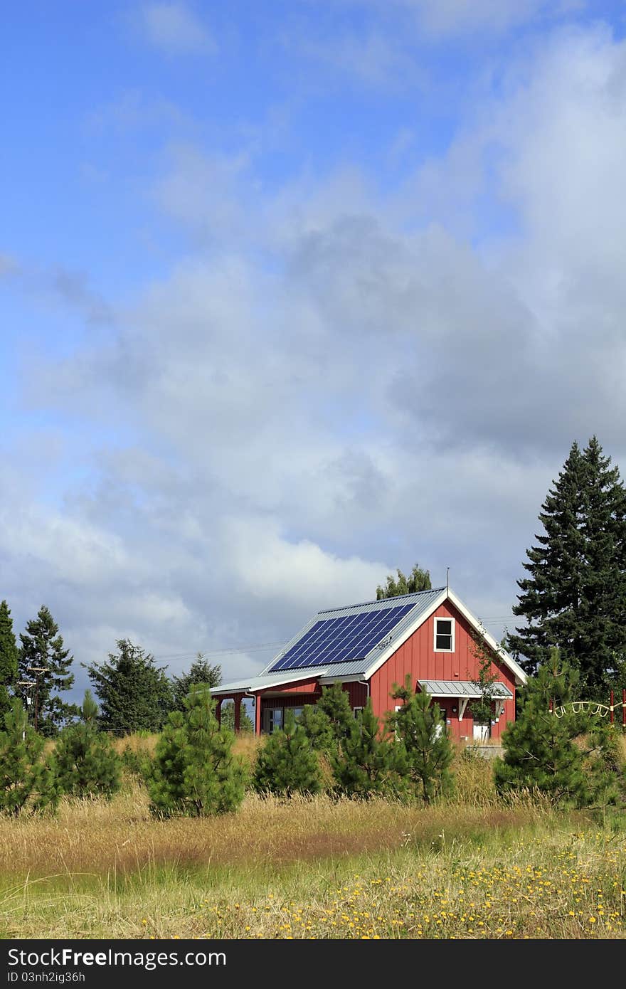 Small, red public park building with solar panels on the metal rooftop on a mostly sunny summer day. Small, red public park building with solar panels on the metal rooftop on a mostly sunny summer day.