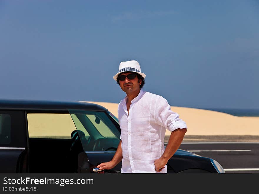 Man in the desert standing close to the car