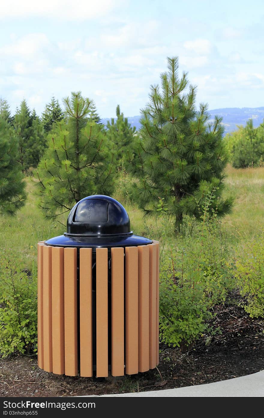 Modern metal and manufactured wood slat garbage can outdoors in a natural landscape park. Modern metal and manufactured wood slat garbage can outdoors in a natural landscape park.