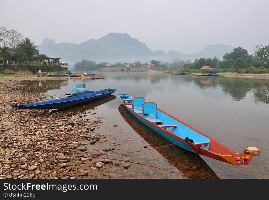 The colorful boats in the shallow river and the mountain on the background. The colorful boats in the shallow river and the mountain on the background