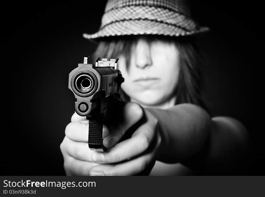 Girl in hat with a big pistol on black background