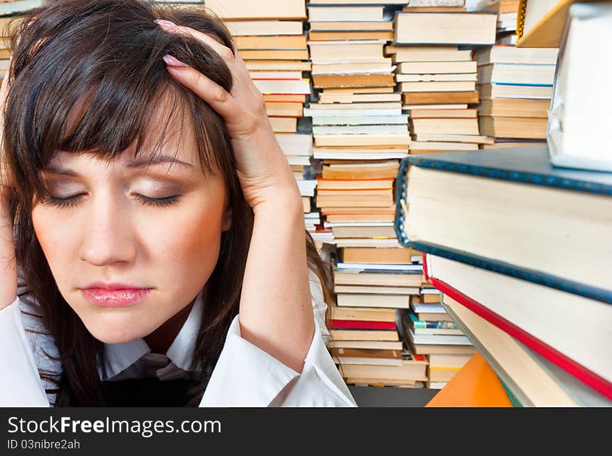 College girl holding her head against many books