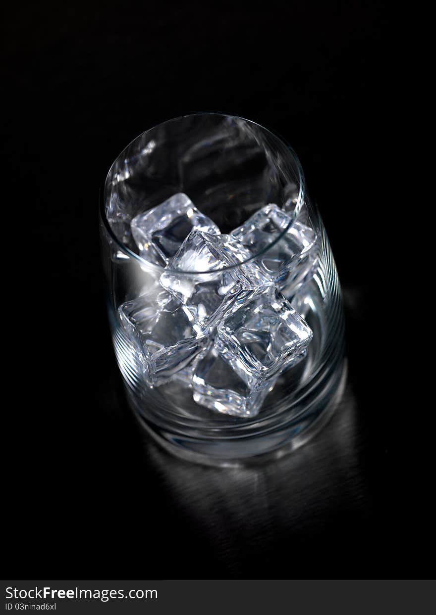 An empty glass on a kitchen bench with ice cubes. An empty glass on a kitchen bench with ice cubes