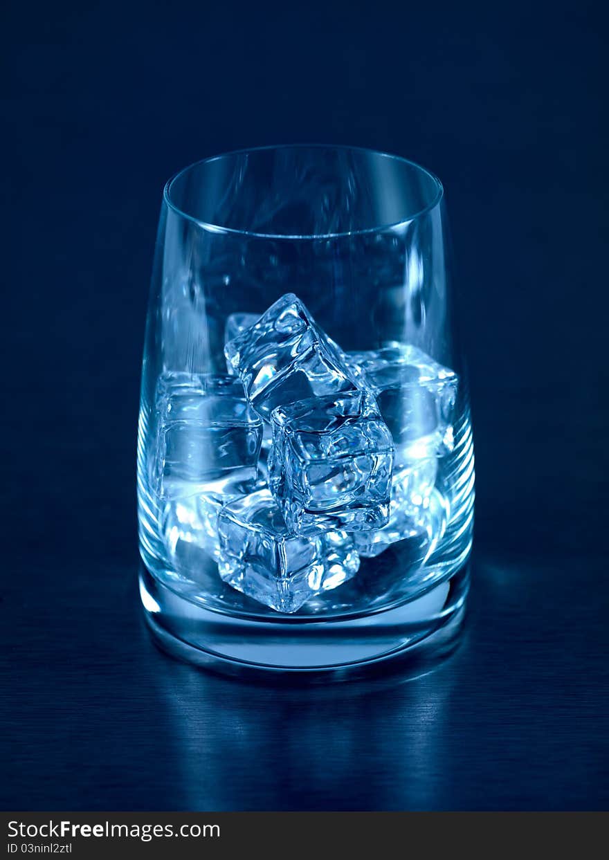 An empty glass on a kitchen bench with ice cubes. An empty glass on a kitchen bench with ice cubes