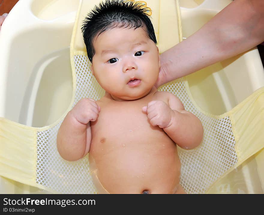 A chinese Baby takes a bath with the help from her mom and father. A chinese Baby takes a bath with the help from her mom and father