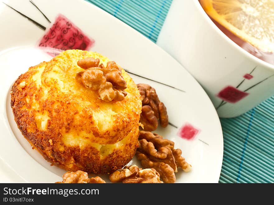 Cheese muffins with walnuts on a plate with tea