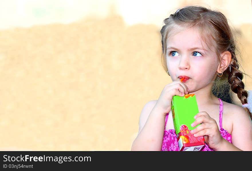 A little girl with blue eyes drinking juice outdoor. A little girl with blue eyes drinking juice outdoor