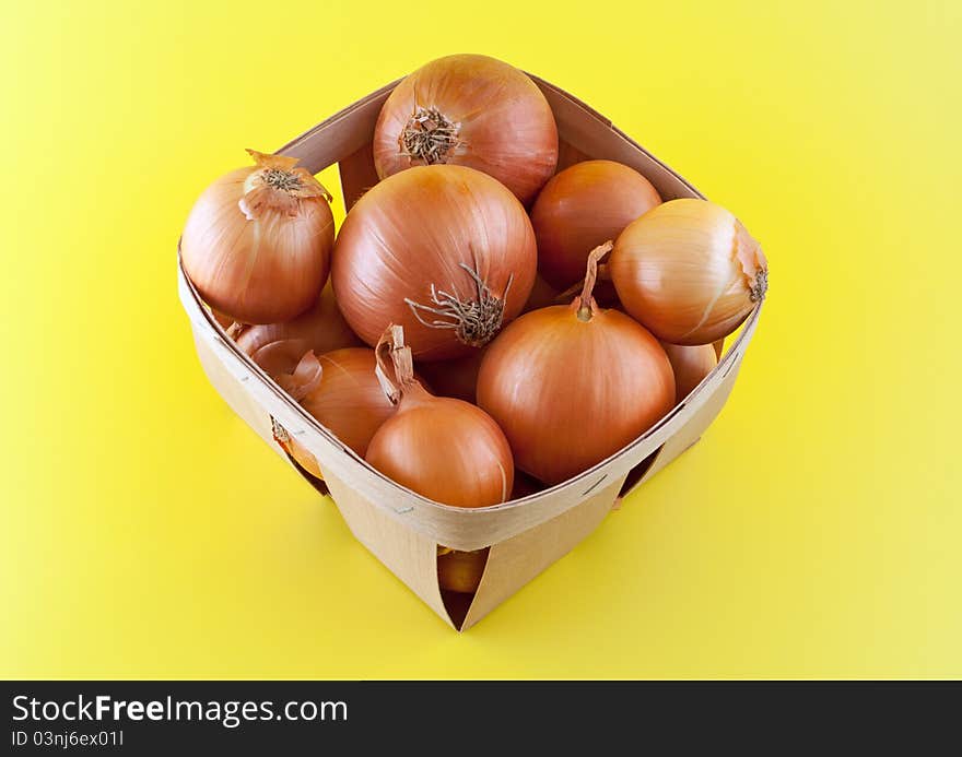 Onions in box on yellow background.