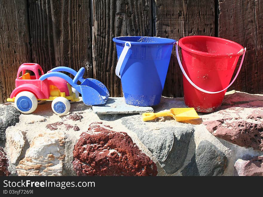 Beach buckets and a toy tractor line dup on a a wall. Beach buckets and a toy tractor line dup on a a wall.