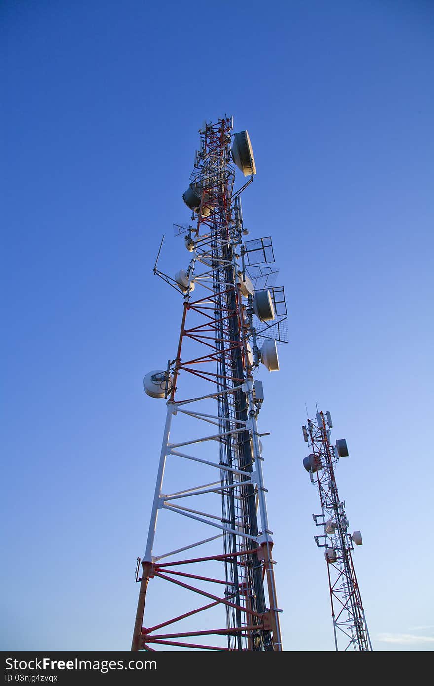 Communication towers on top of hill with blue sky background