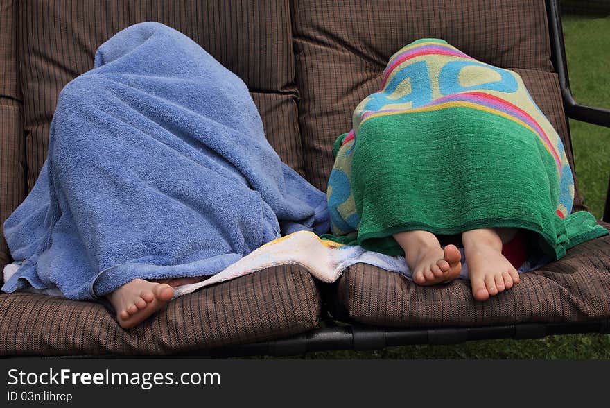 Two kids on a chair hidding with towels. Two kids on a chair hidding with towels