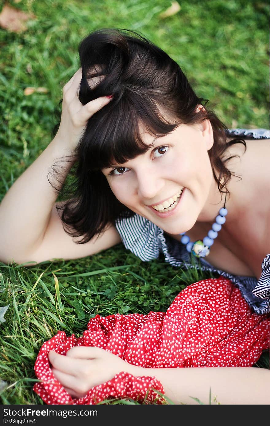 Attractive girl, lying on a grass and smiling. Close up.