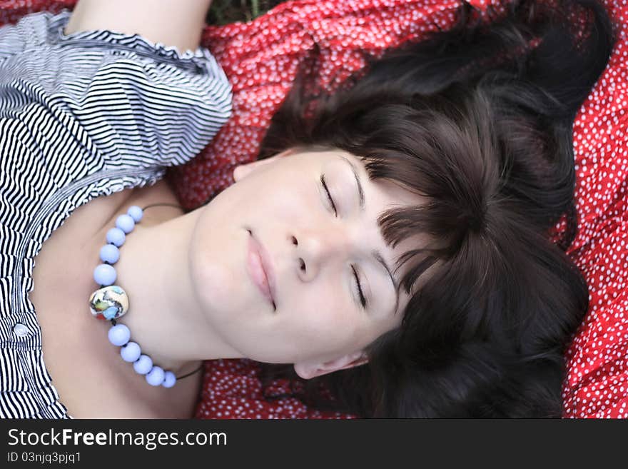 Attractive girl, lying on a grass and smiling. Close up. Attractive girl, lying on a grass and smiling. Close up.