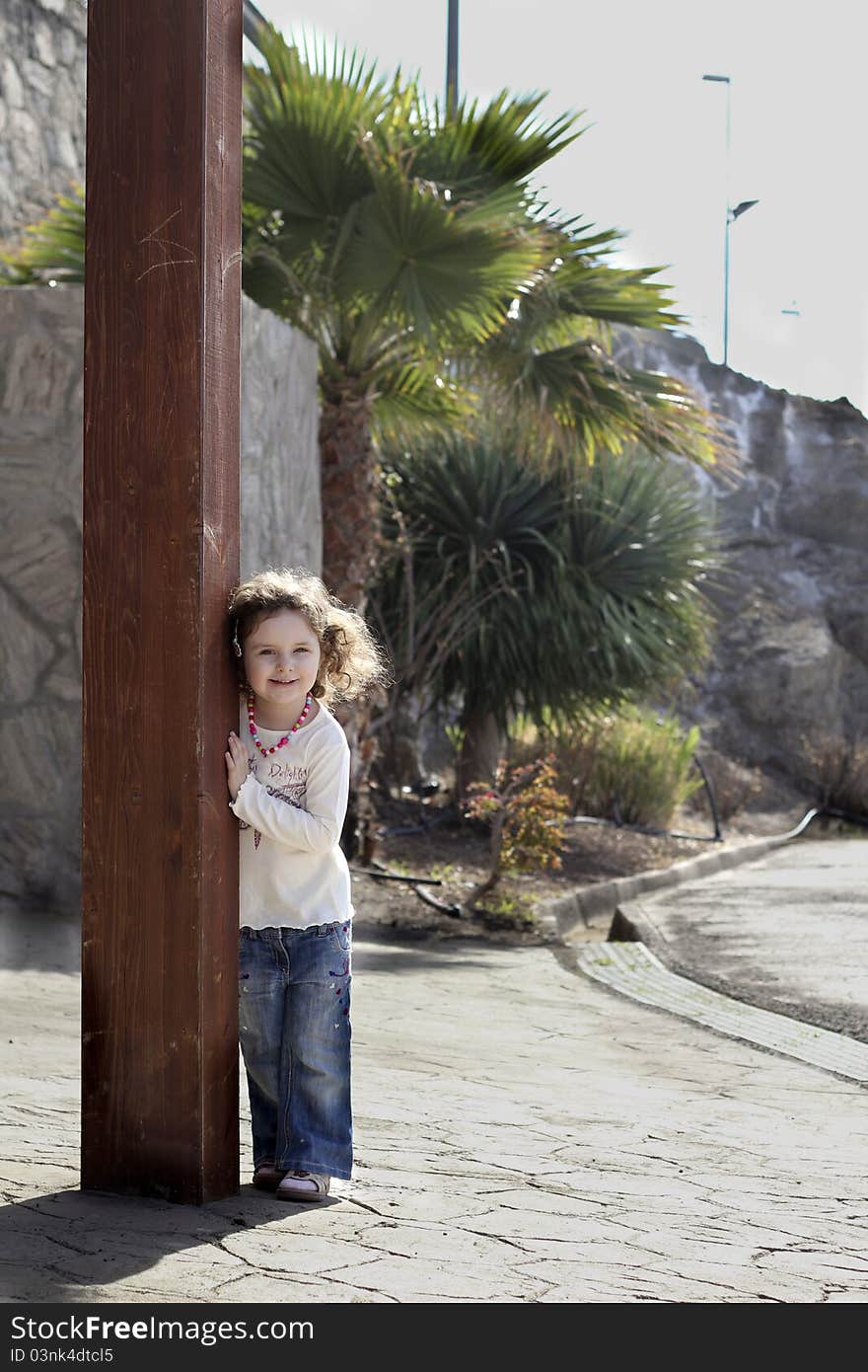 Smiling toddler peeks from behind a column