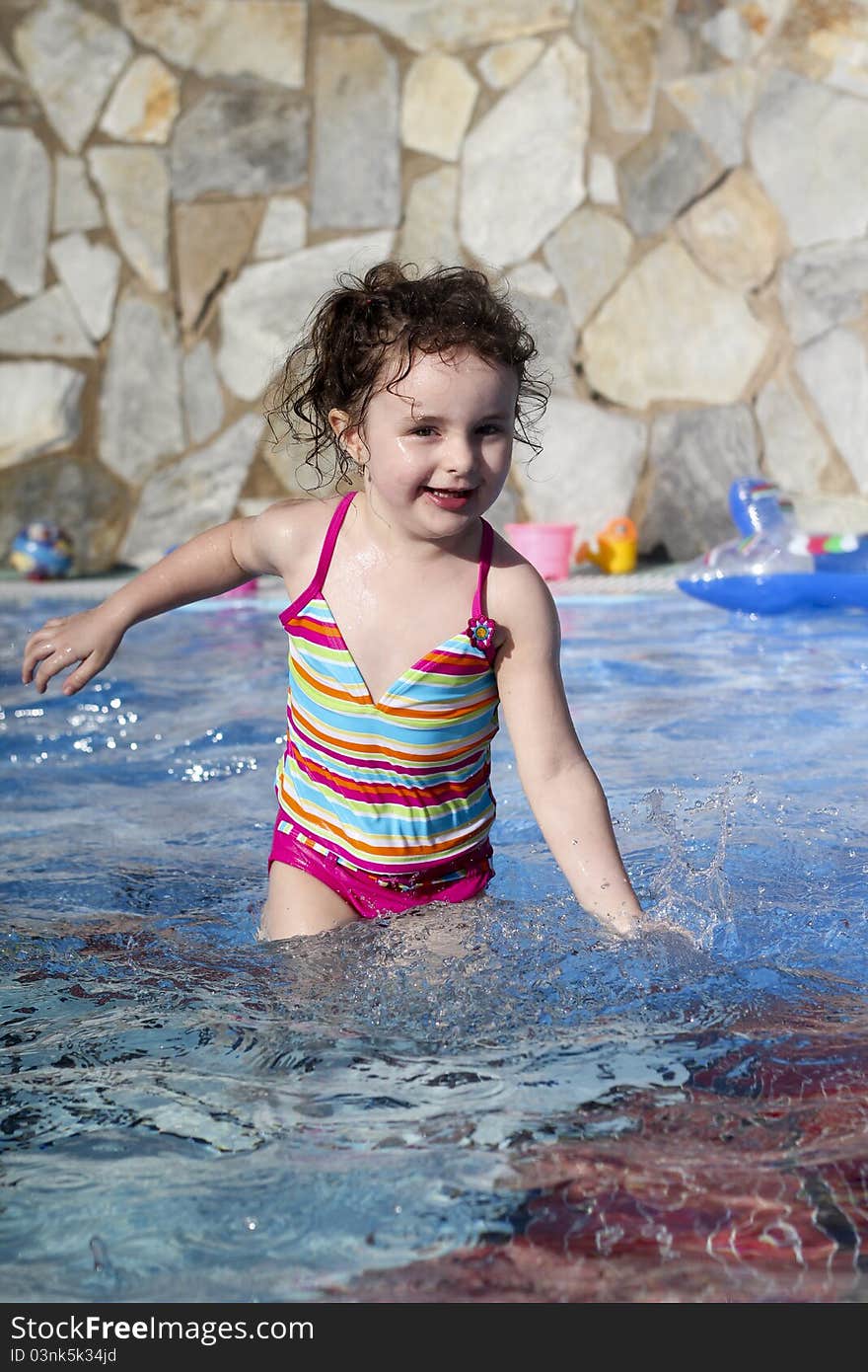 Small girl is playing in the swimming pool