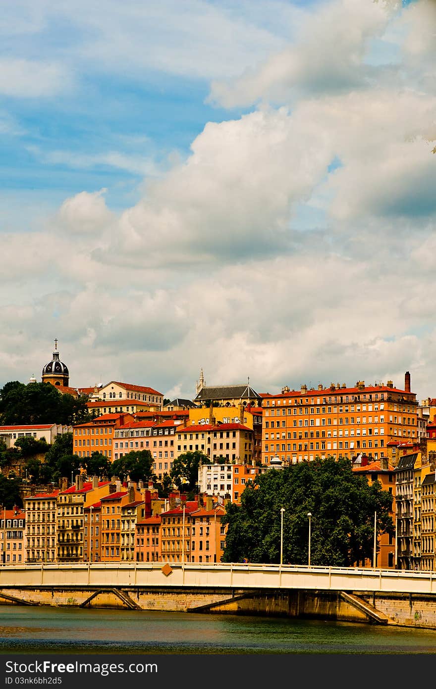 A bright day in the city of Lyon the colourful stone buildings sit near the bridge under big white clouds one day in summer. A bright day in the city of Lyon the colourful stone buildings sit near the bridge under big white clouds one day in summer.