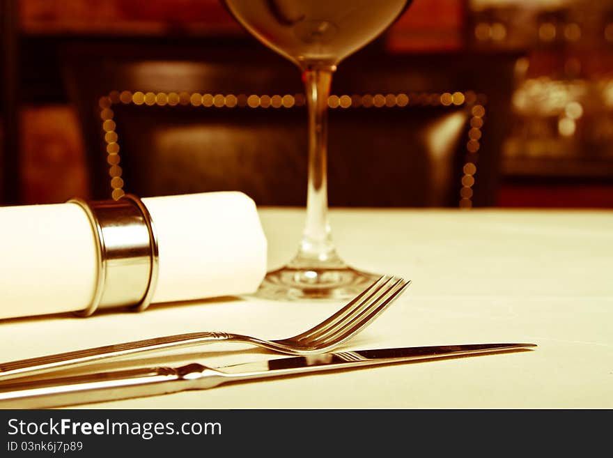 Silverware besides a glass of wine (warm filter). Silverware besides a glass of wine (warm filter)