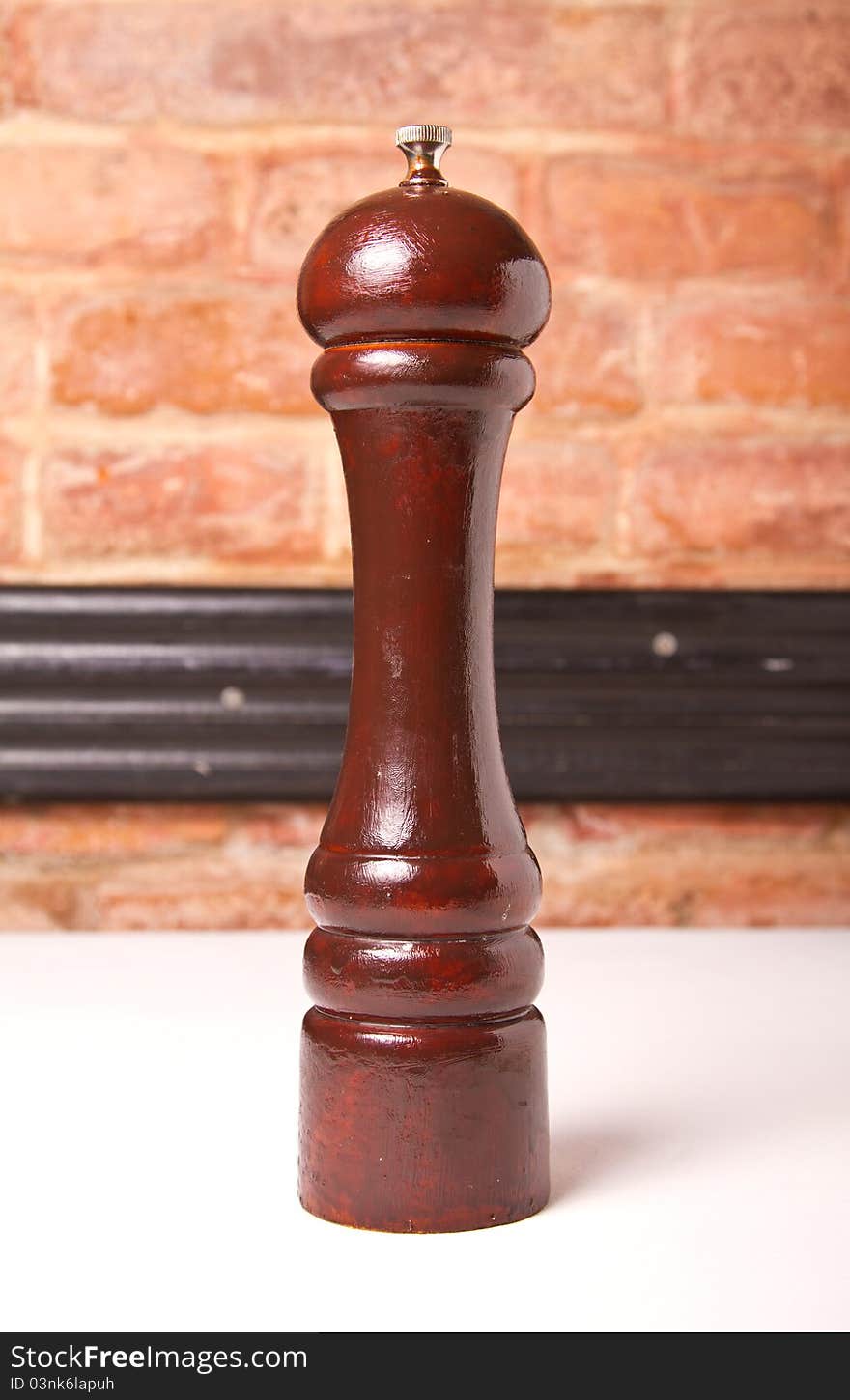 Pepper wooden grinder with brick wall in the background. Pepper wooden grinder with brick wall in the background